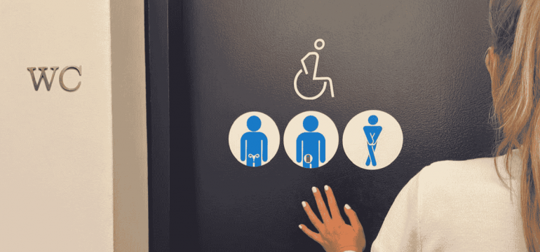 Woman standing at the entrance of an accessible washroom, featuring inclusive washroom signage
