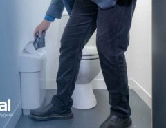 Image showing a man disposing of incontinence waste in a sanitary bin located inside a bathroom cubicle