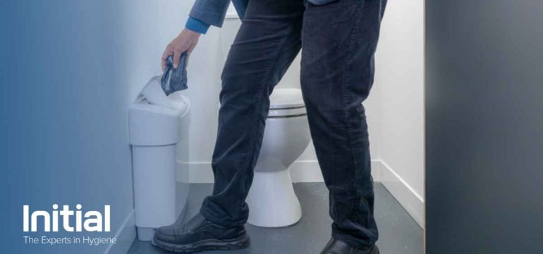 Image showing a man disposing of incontinence waste in a sanitary bin located inside a bathroom cubicle