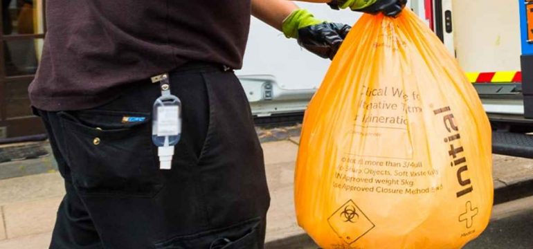 Initial Medical technician holding clinical wasted disposal bag