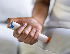 a person holding and injecting an AAI (Auto Adrenaline Injection) with their right arm onto their right leg